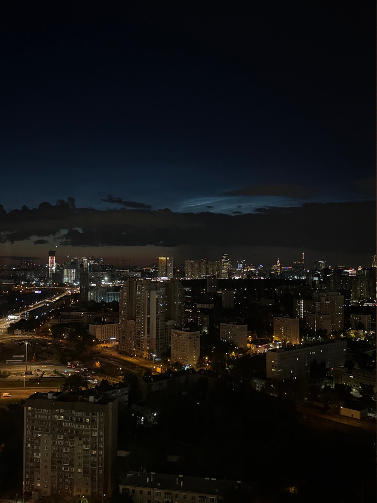 City lights meet stormy skies in a nighttime aerial panorama