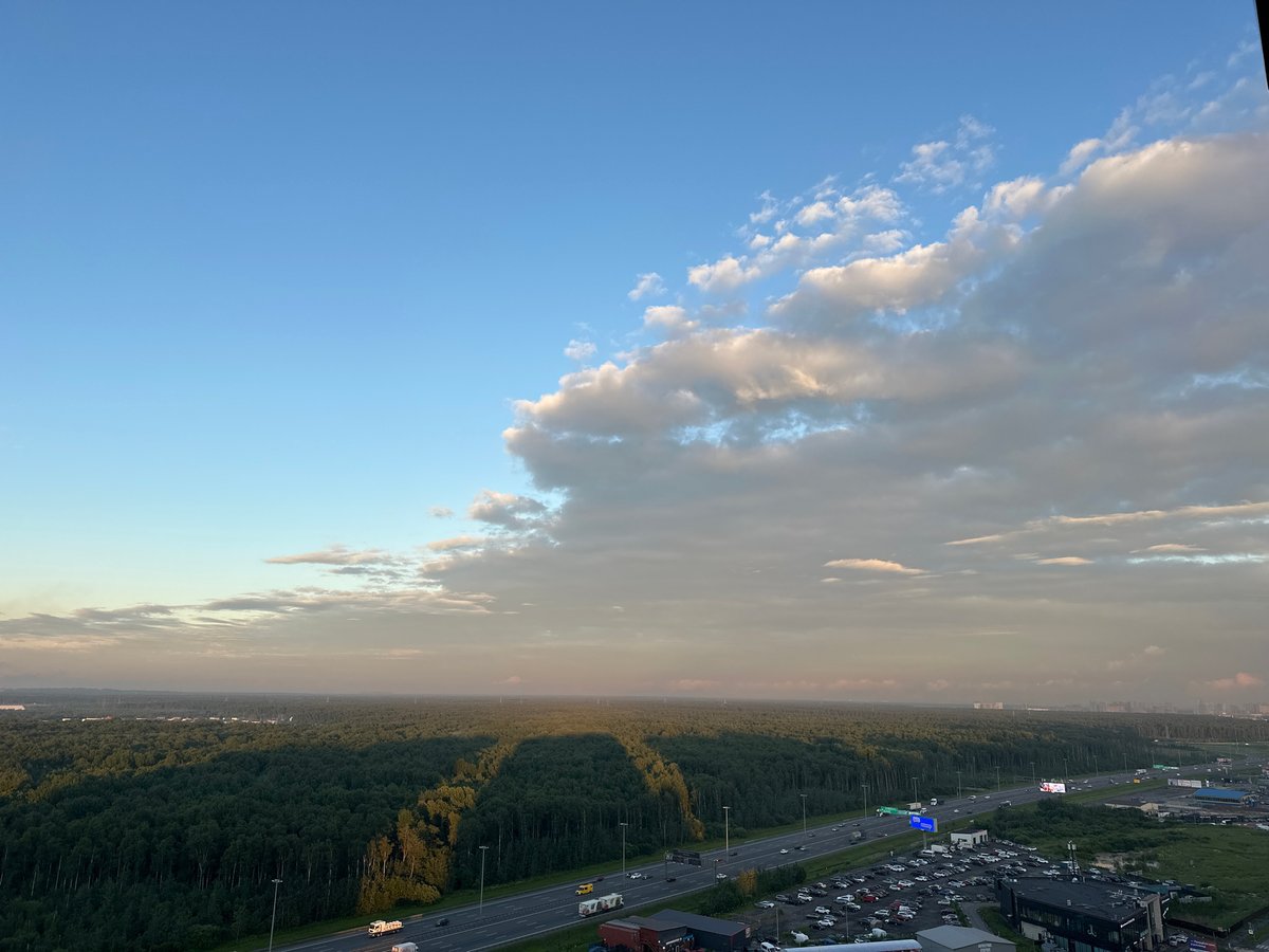 Kudrovo at golden hour: forest, highway, and apartment towers