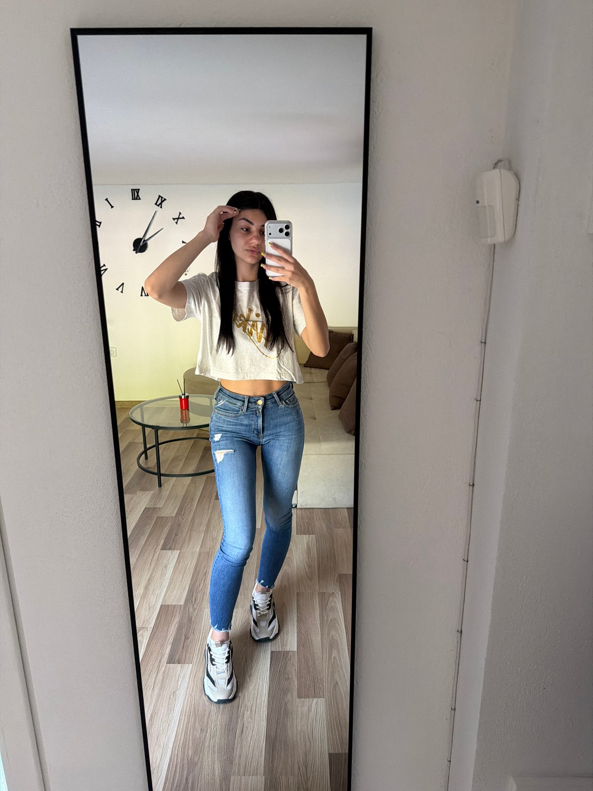 Young woman takes mirror selfie in casual attire