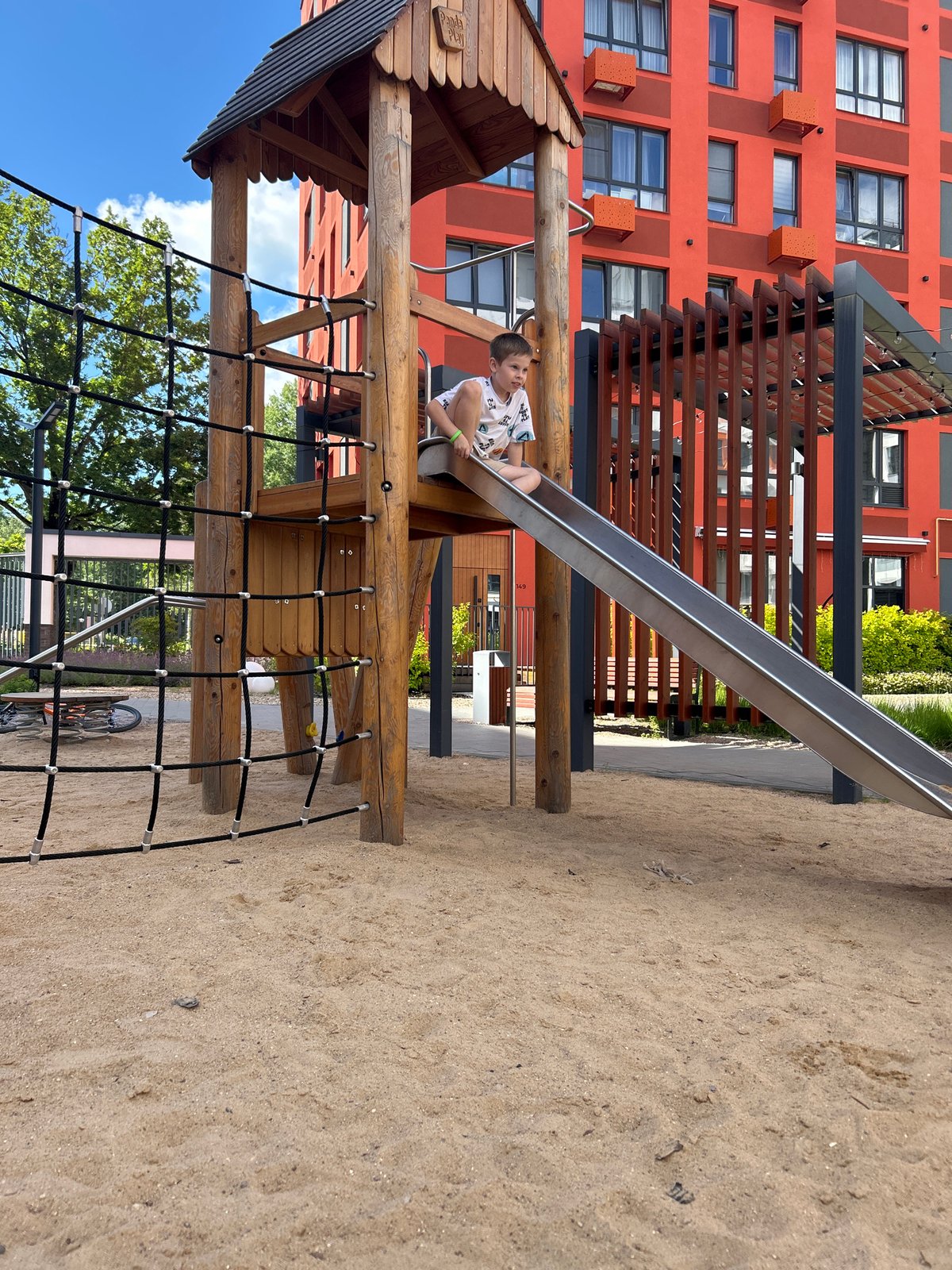 Sunny afternoon at a Kaluga playground, kids and sandbox in full swing.