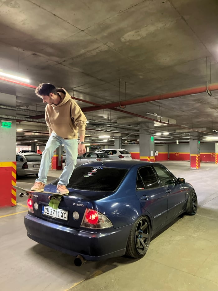 Young man performs skateboard stunts on cars in Sofia garage