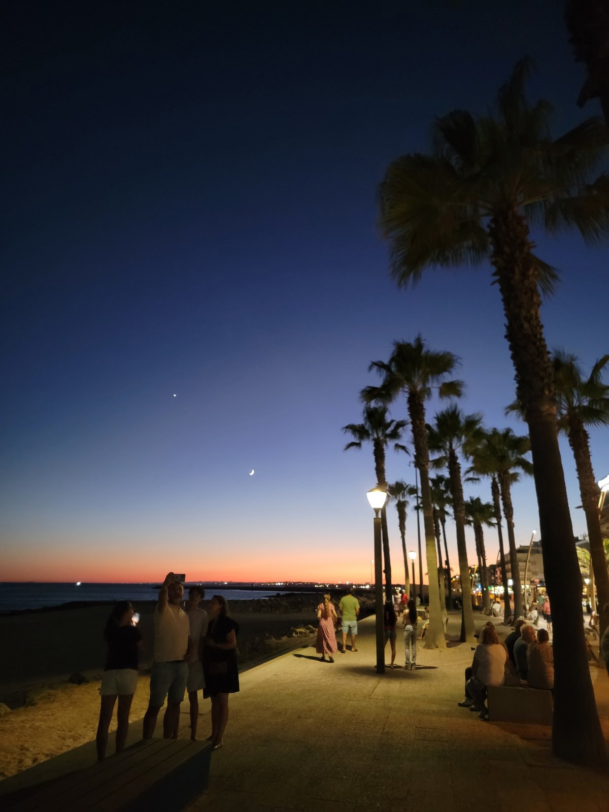 Twilight on the Quarteira promenade, neon signs coming alive