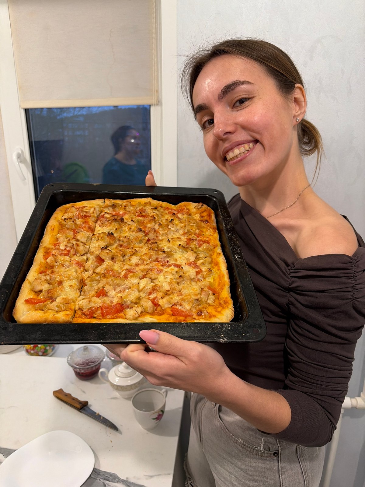 Woman displays homemade pizza in Sarapul kitchen