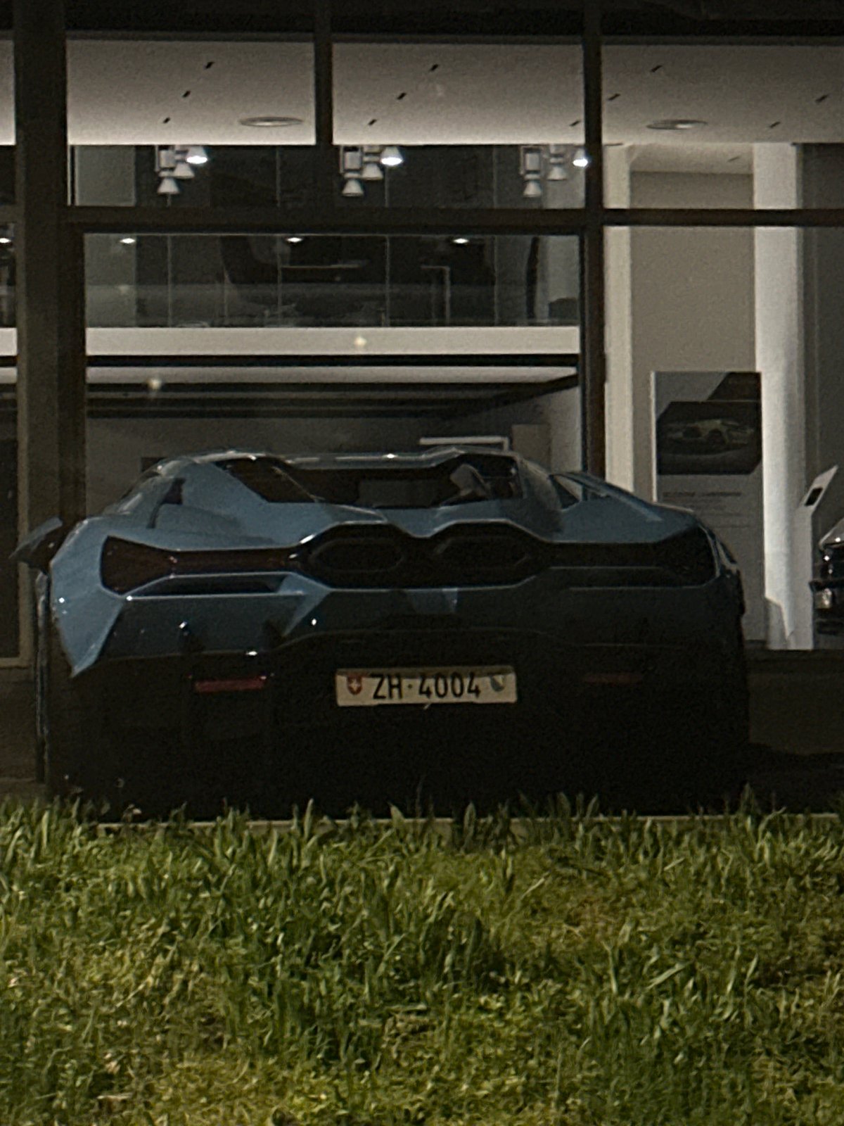 Blue BMW M4 parked near luxury dealership in Kloten