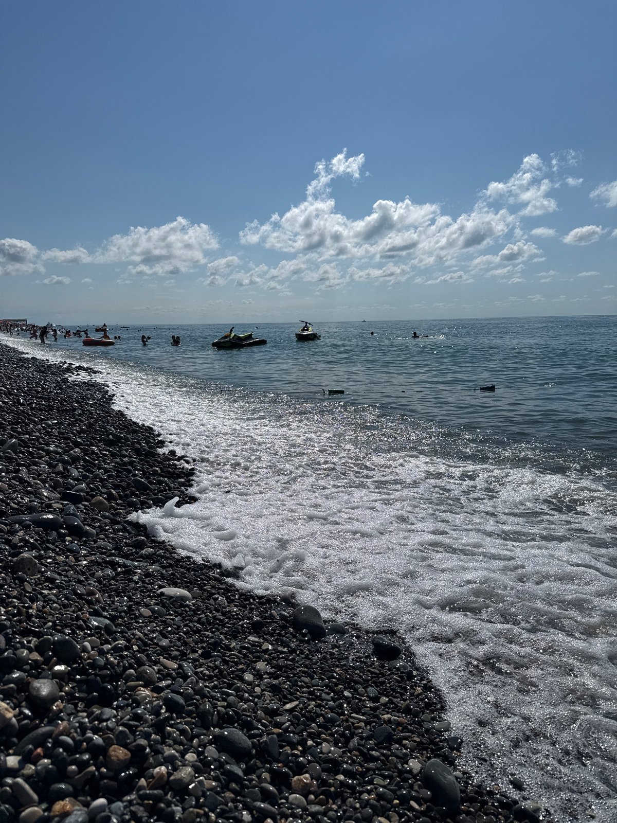 Sun, pebbles, and crowds at a bustling beach