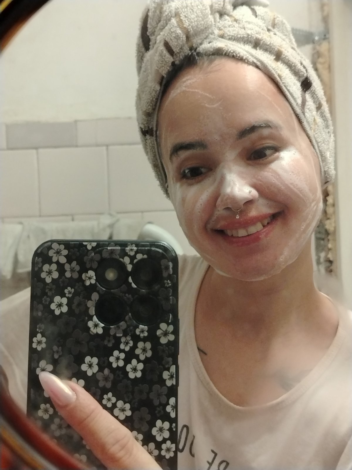 Mirror selfie mid-cleanse, foam on face and towel on head.