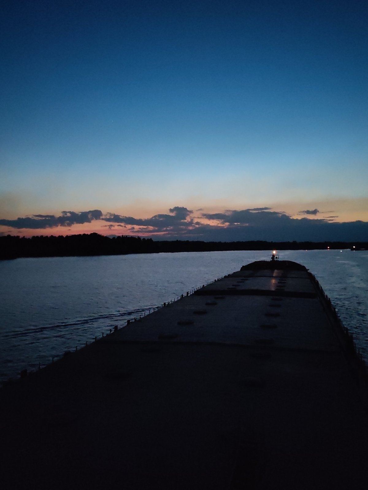 Nighttime waterway scenes show barge and illuminated cable-stayed bridge