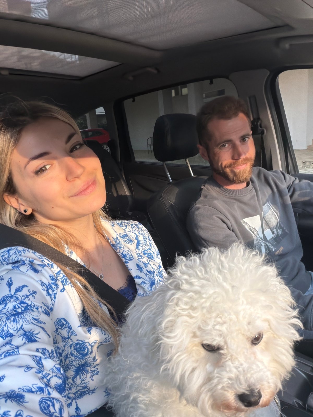 Couple travels with fluffy white dog through sunny Budva