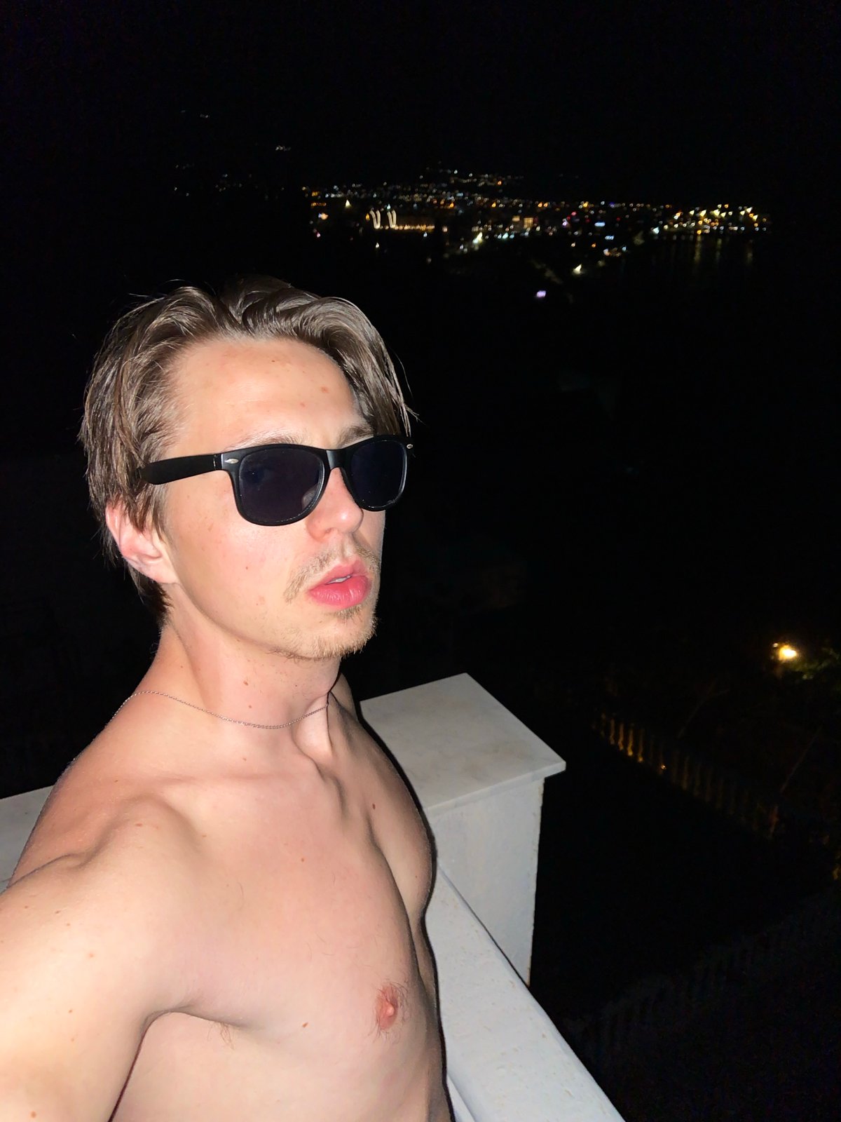 Man poses for nighttime photos on ledge in Šušanj