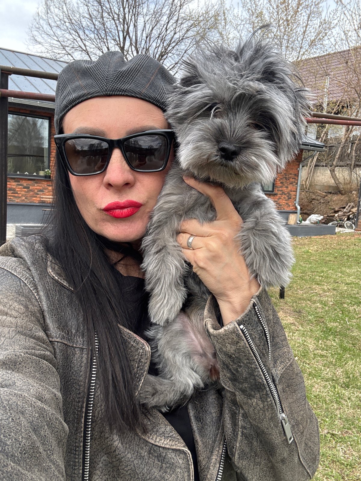 Woman with small grey dog photographed outdoors in Chaikovsky