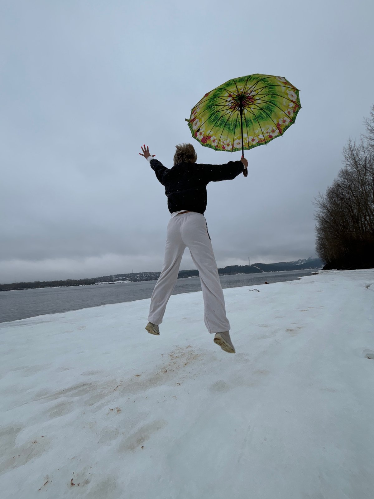 Person caught mid-air with umbrella on snowy ground in Russia
