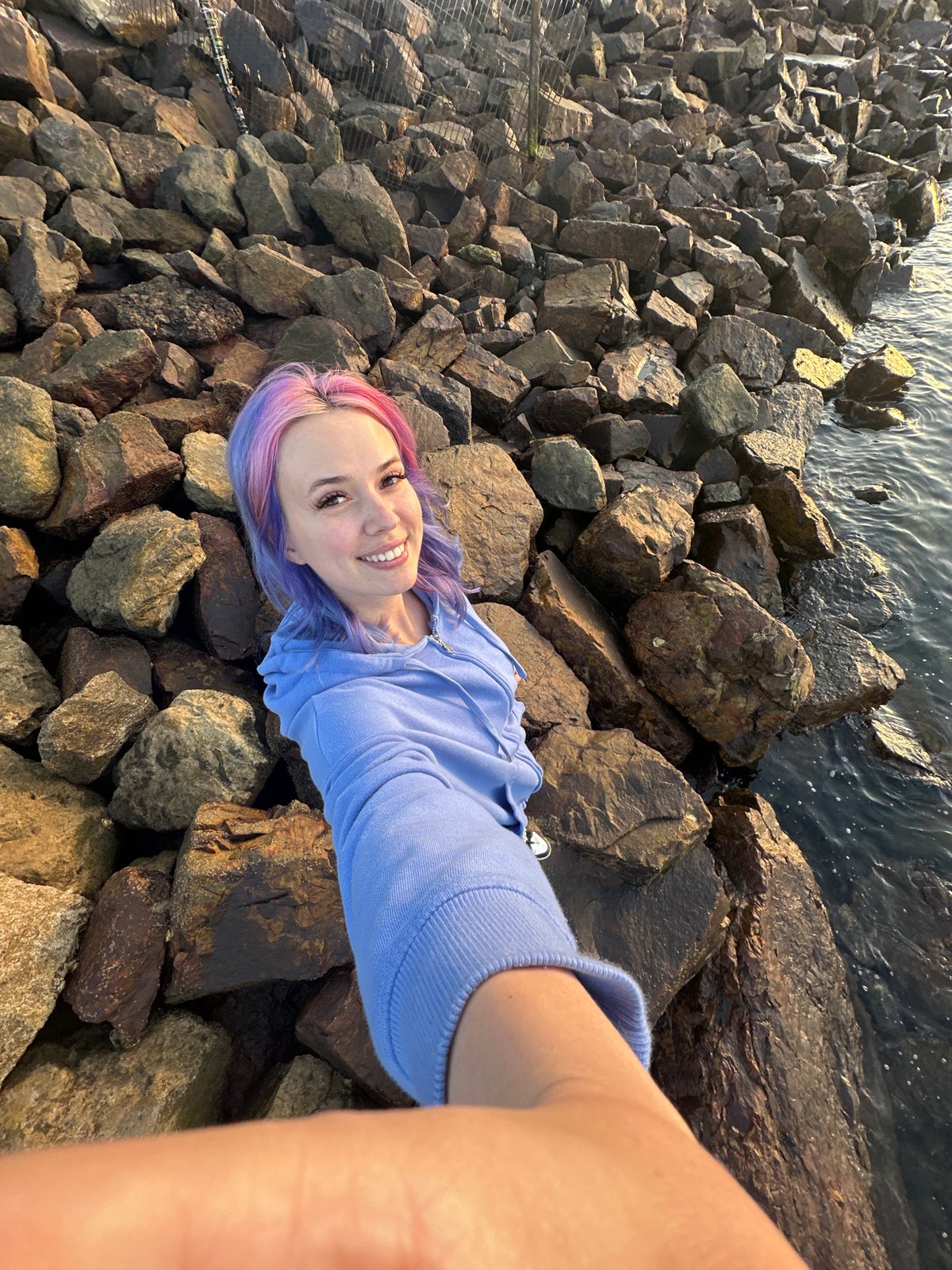 Woman documents sunset walk with dog along Gijón coastline