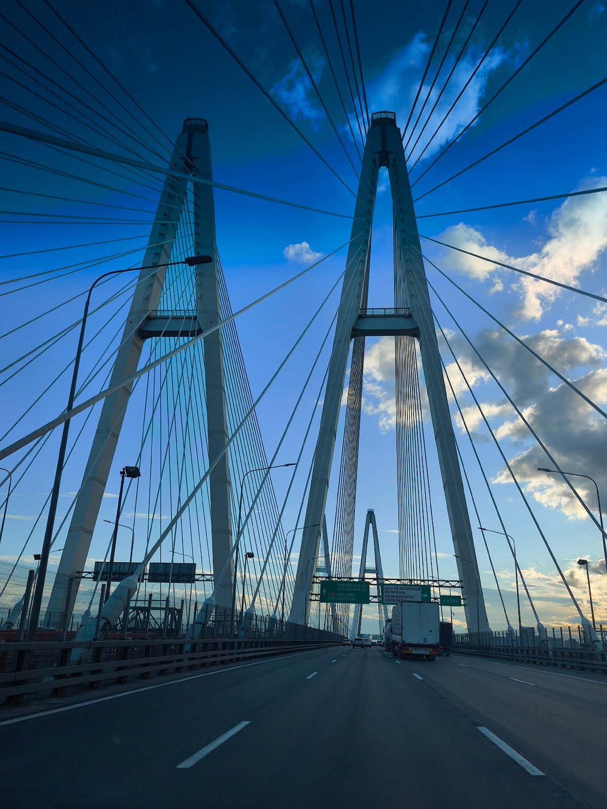 Vehicle crosses cable-stayed bridge on clear afternoon