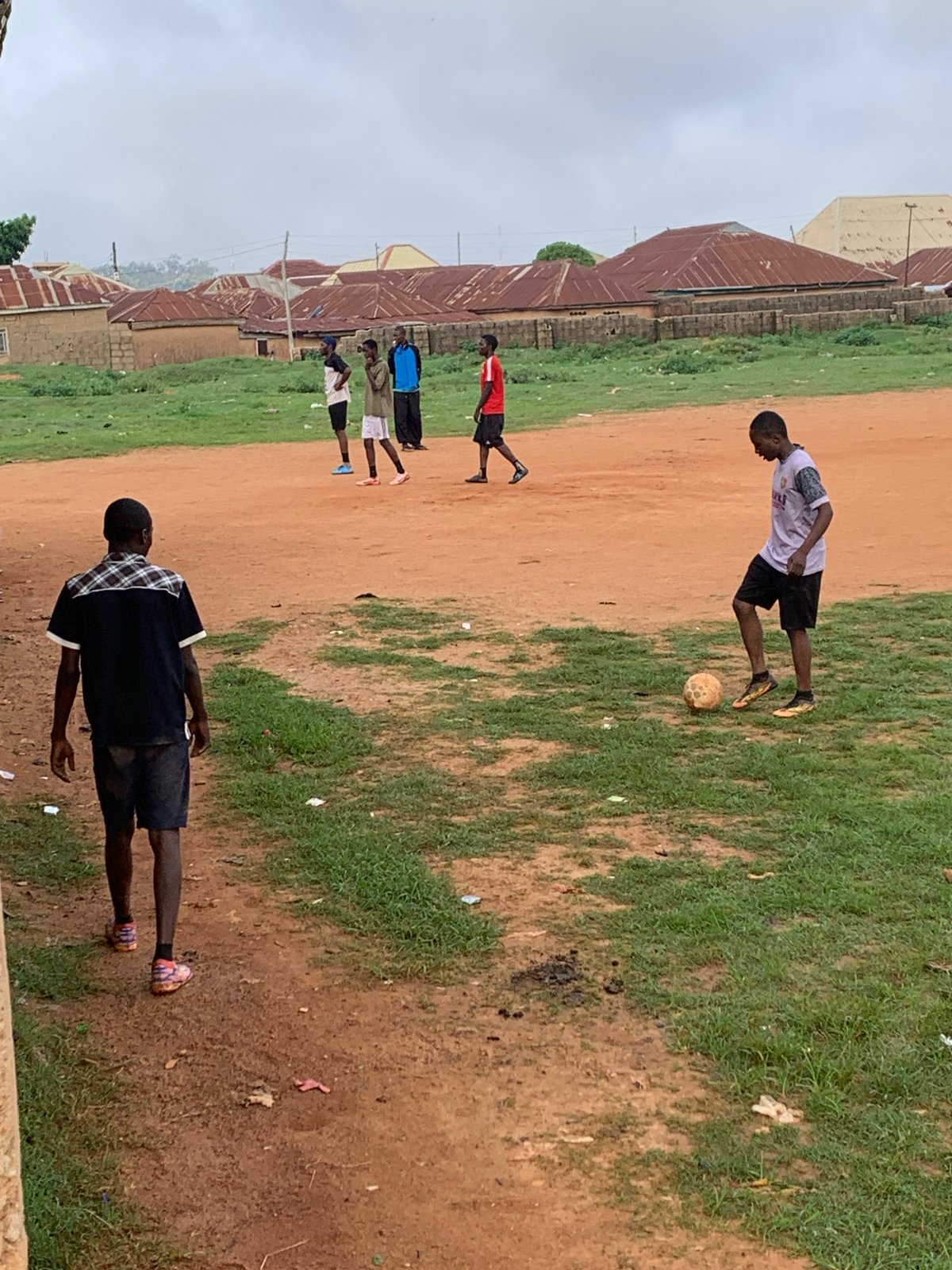 Pickup soccer game on a red dirt field in Bukuru, Nigeria.