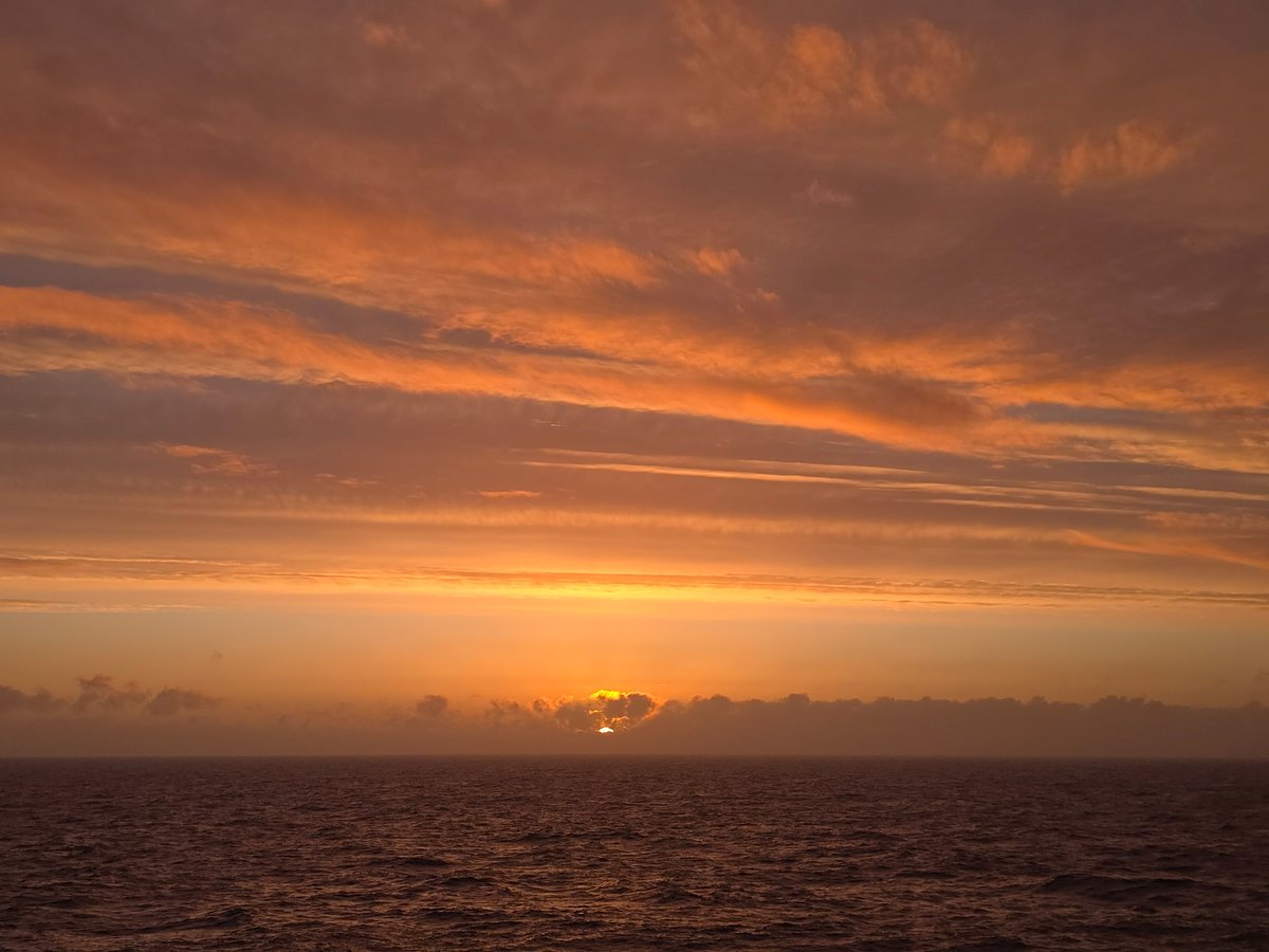 Sunset observed over ocean with orange-pink sky near Norway
