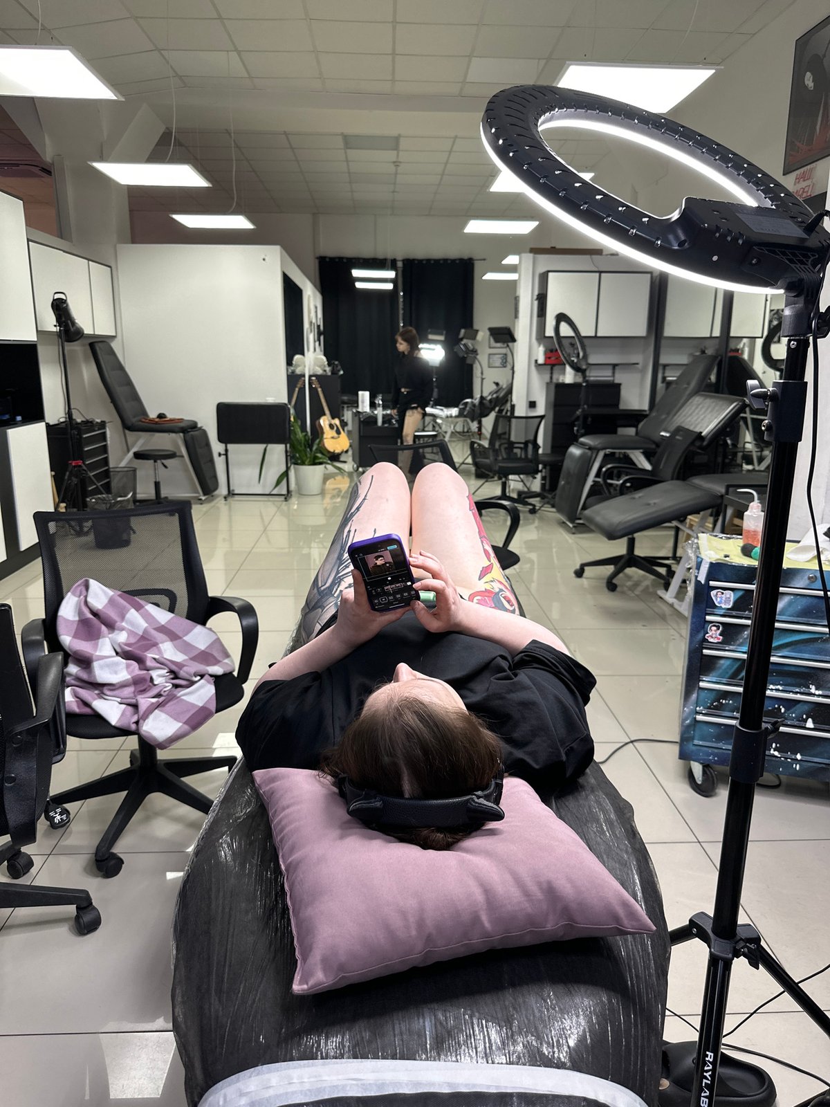 Person gets tattooed while using phone in Rostov studio