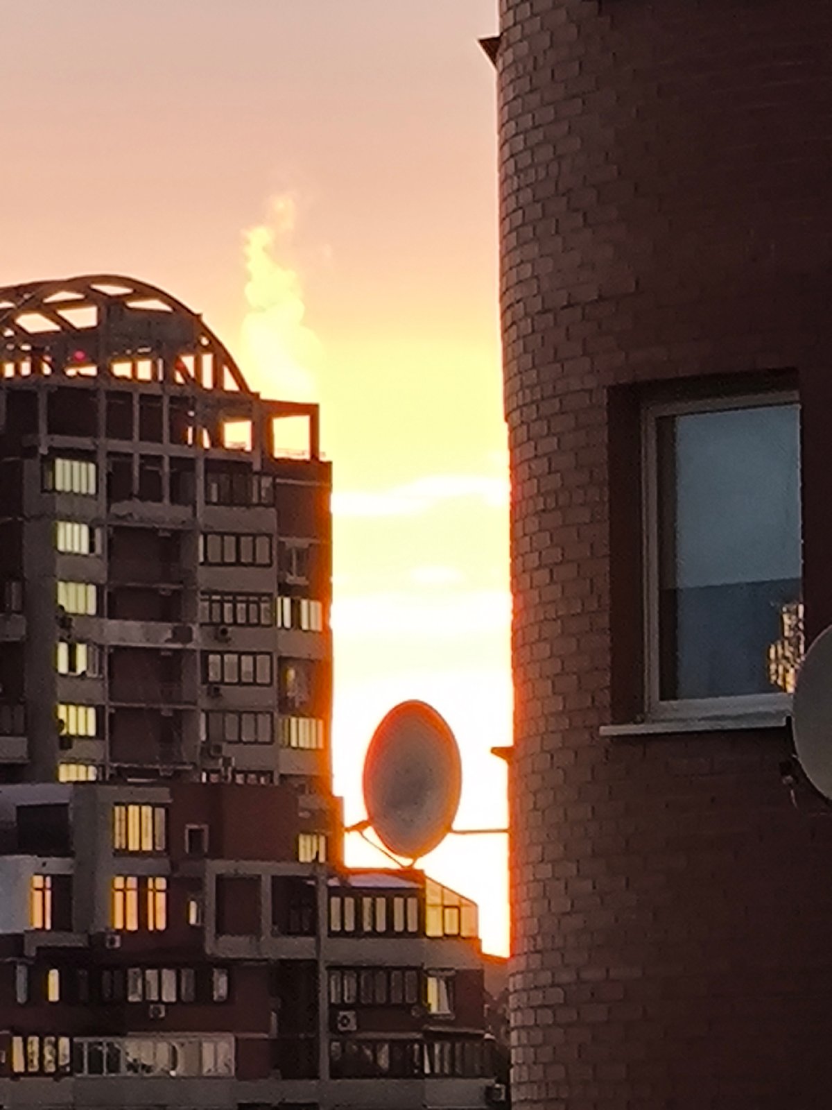 City skyline glows at dusk, construction towers included