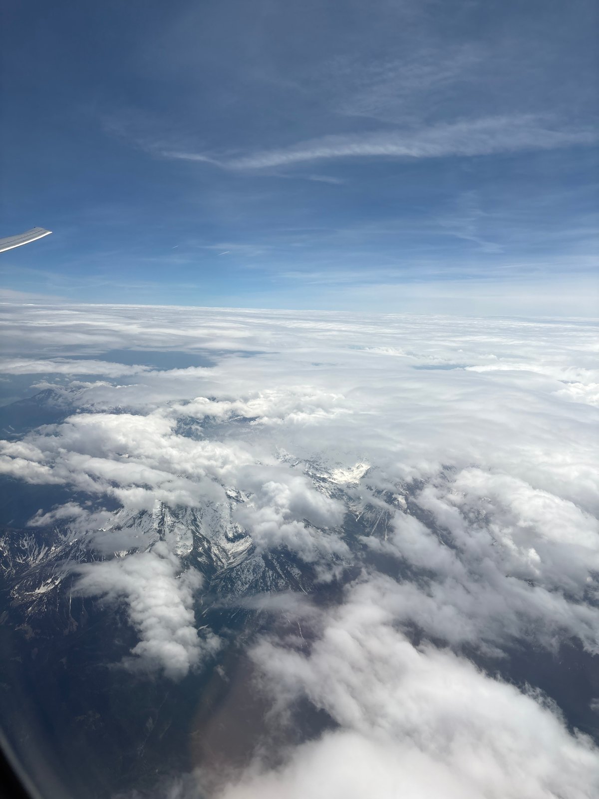 Aerial view captured from airplane window over mountains and clouds