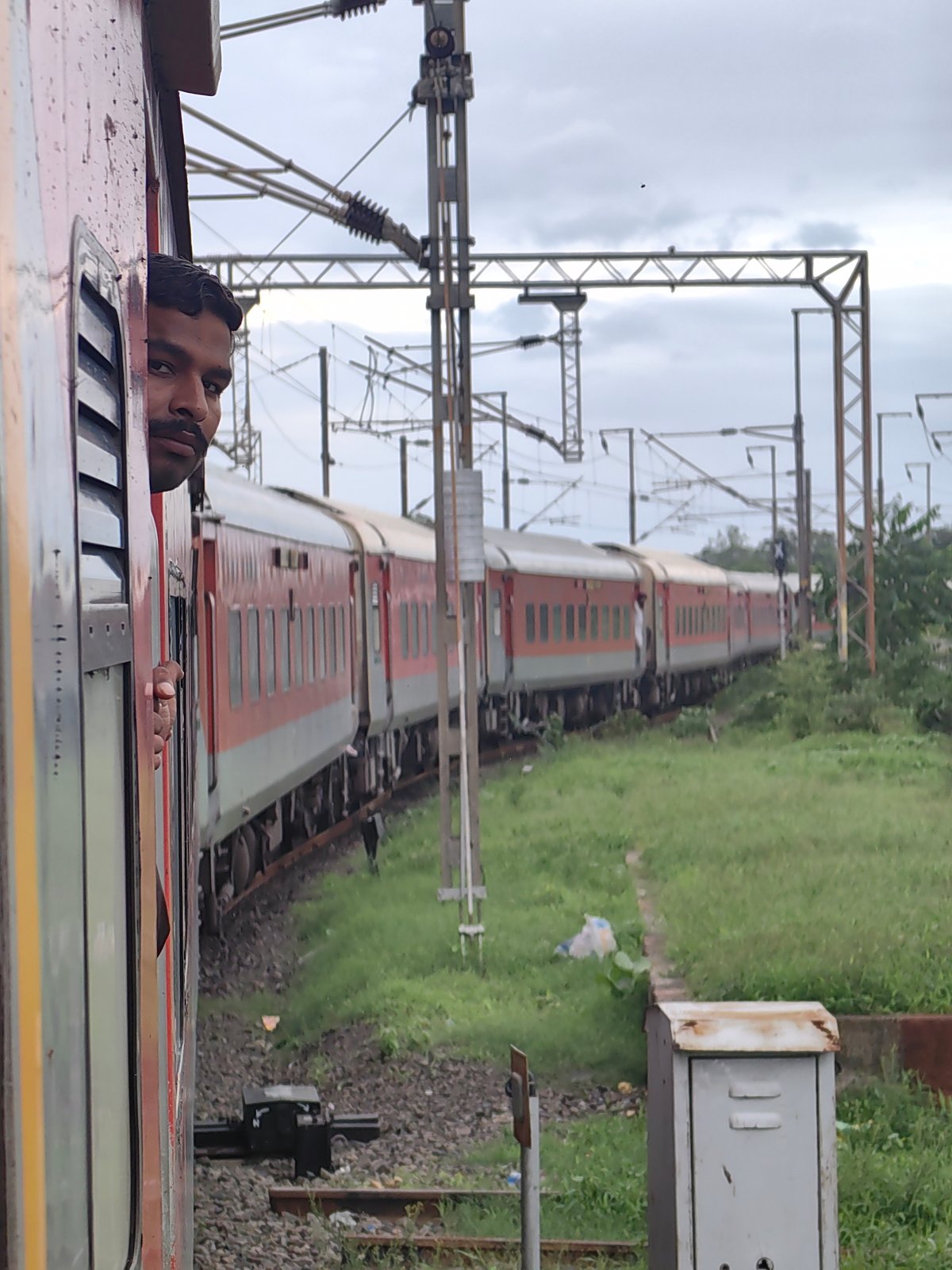 Passenger train moving through green countryside near Kandari, India