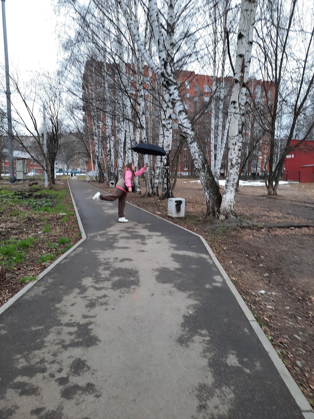 Pedestrians navigate wet sidewalks in Izhevsk during afternoon