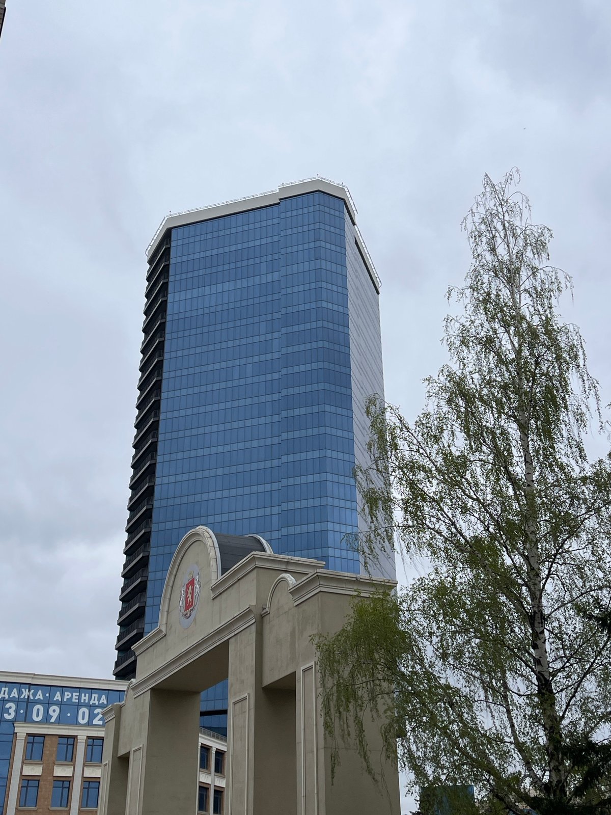 Glass skyscraper observed through trees in Krasnoyarsk, Russia