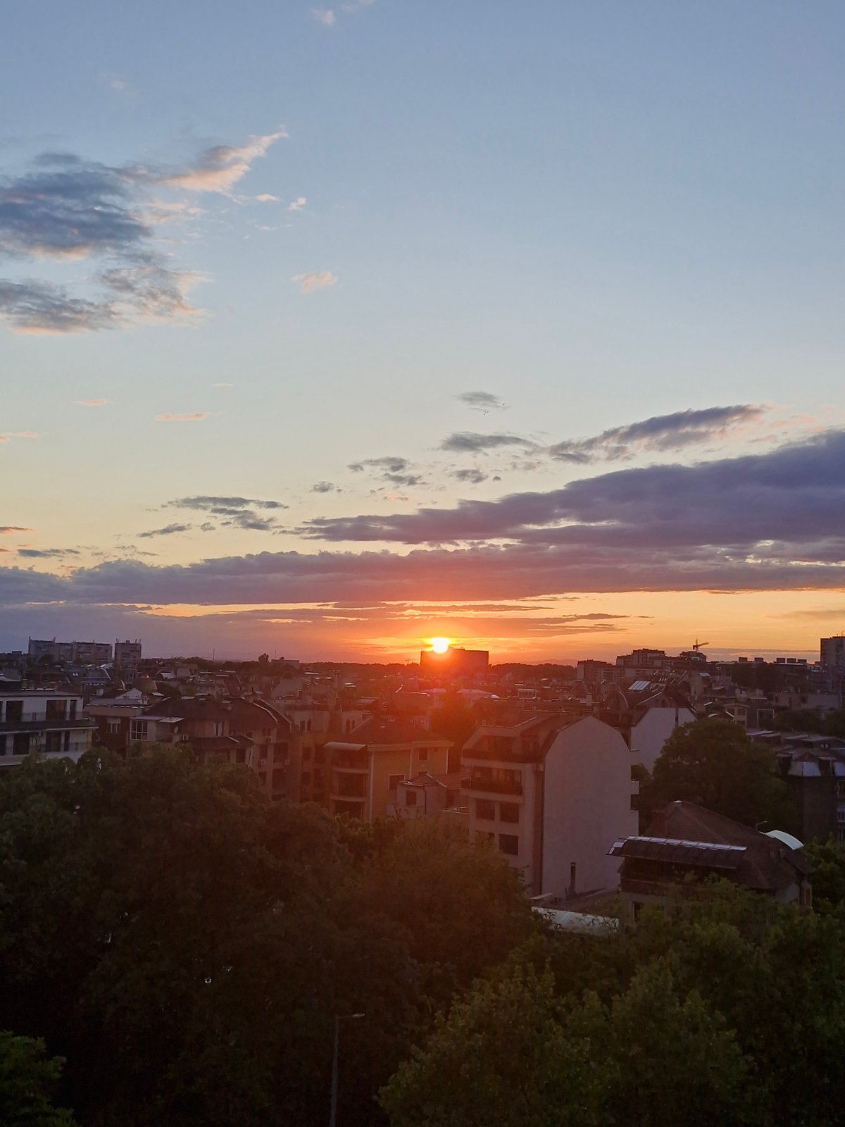Urban sunset observed with orange sun, gradient sky colors