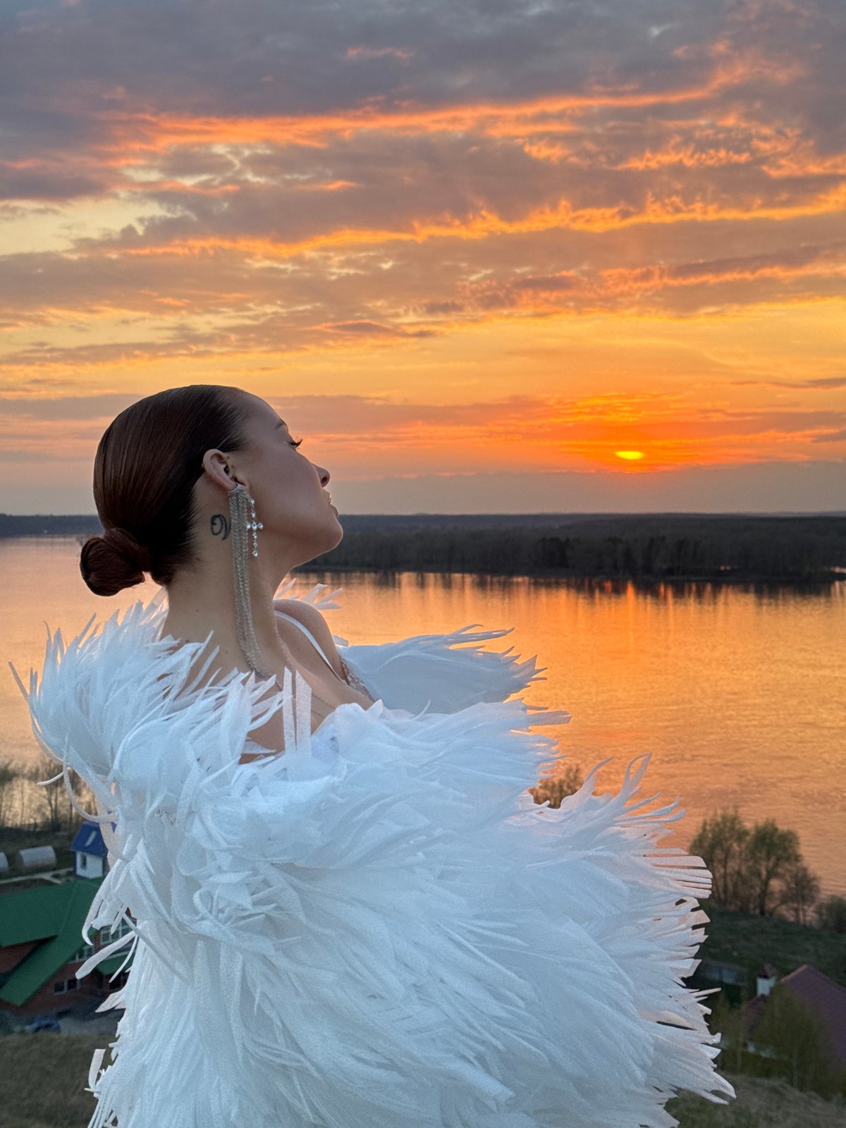 Woman in white feathers gazes skyward in Ольховка