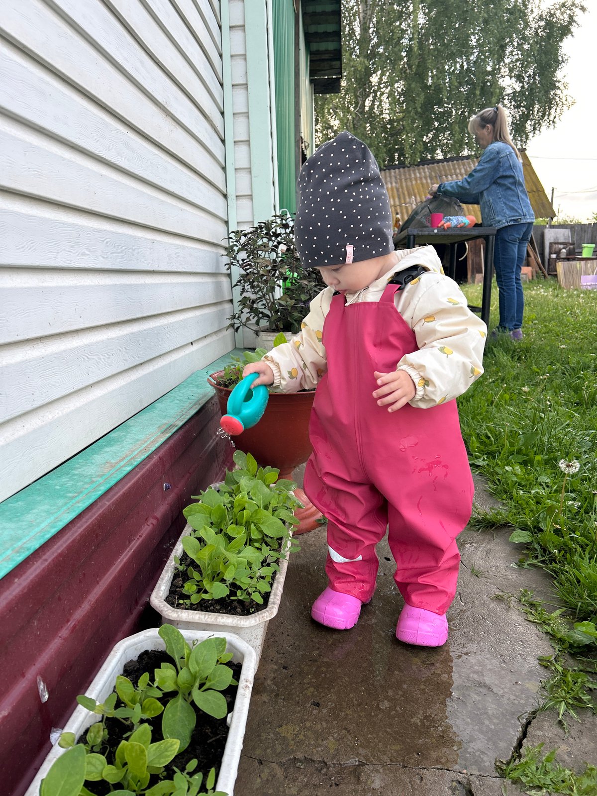 Toddler plays outdoors in rain gear in Азинский, Russia