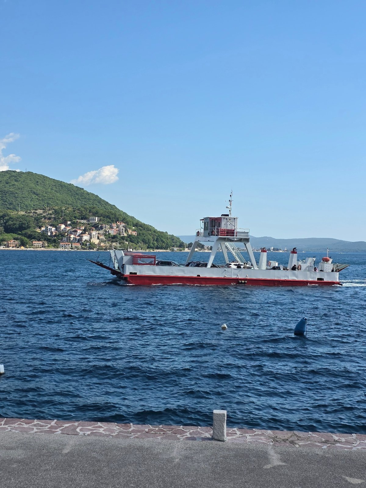 Ferries cross calm waters near Đurići, Montenegro coastline