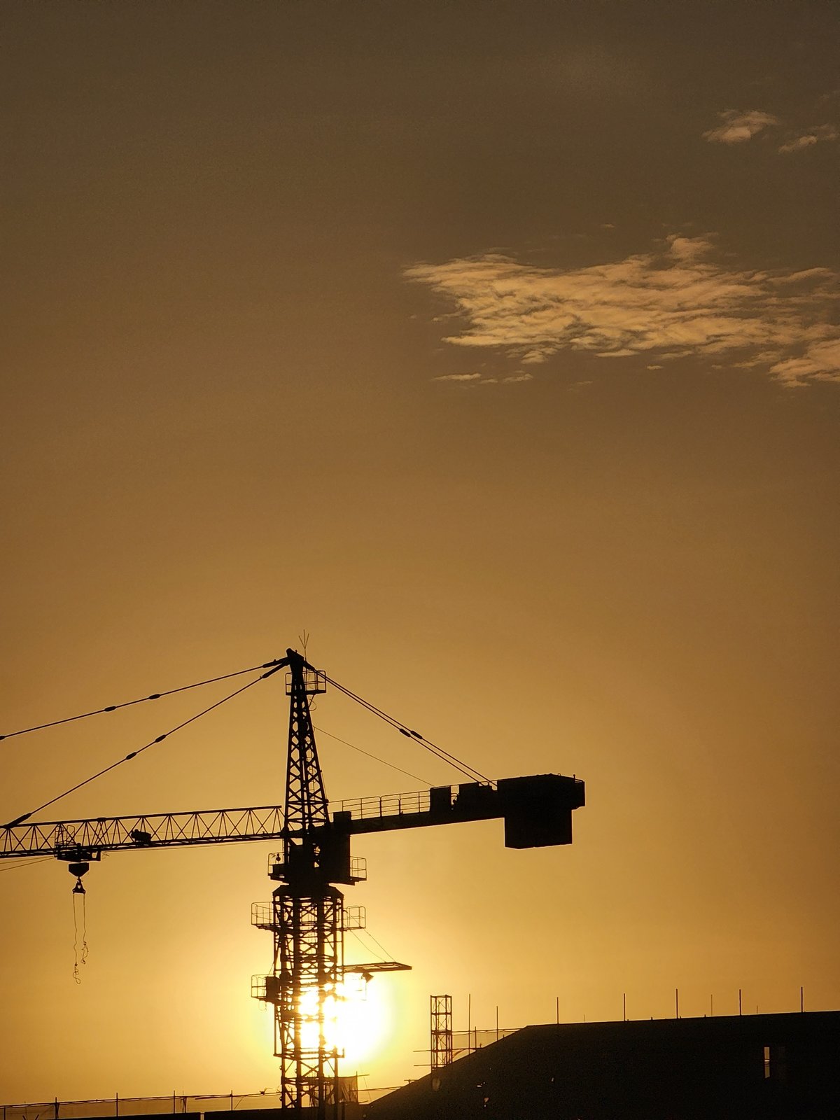 Construction crane silhouette captured against golden sky