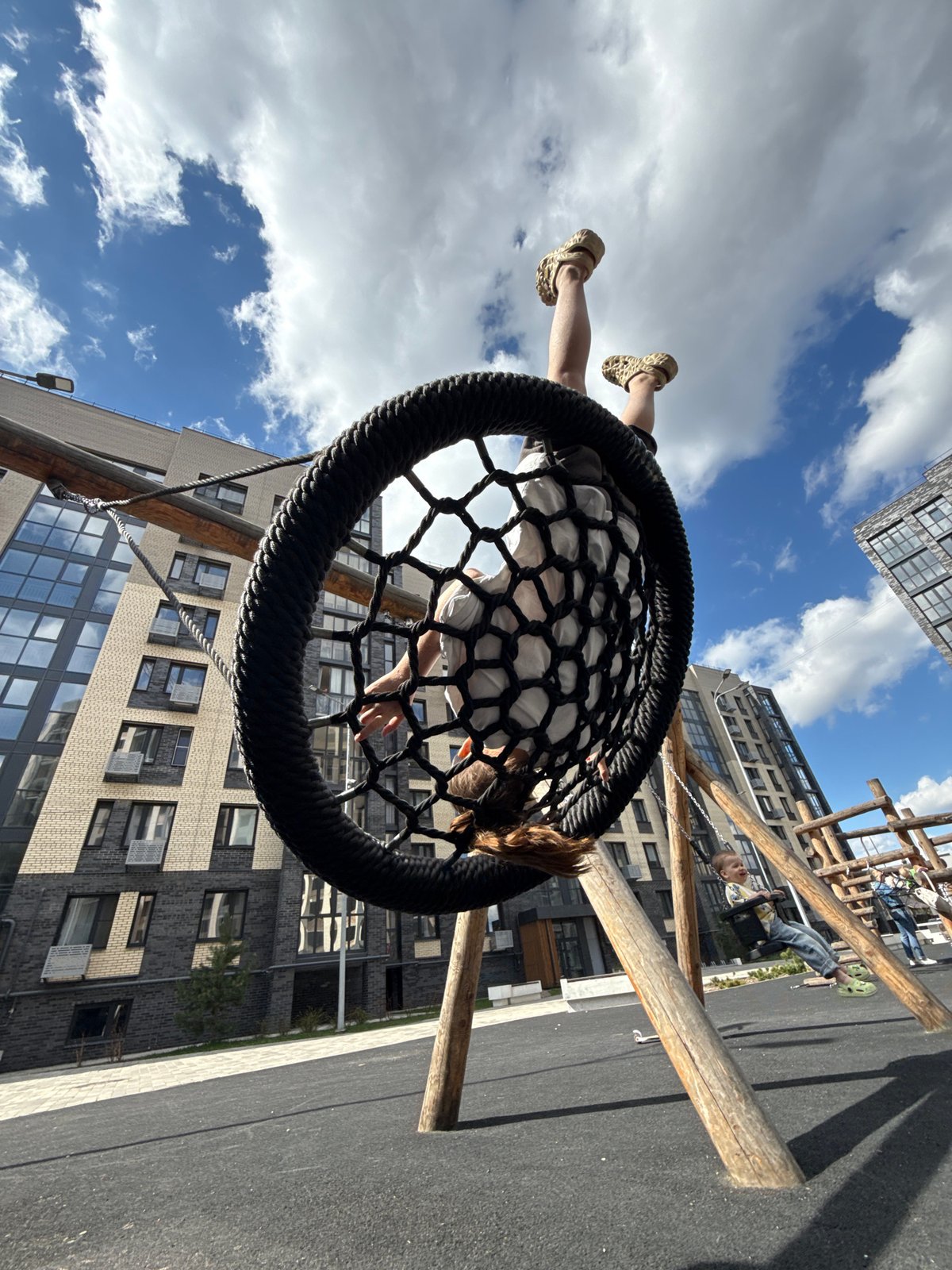 Child plays on basket swing in urban playground