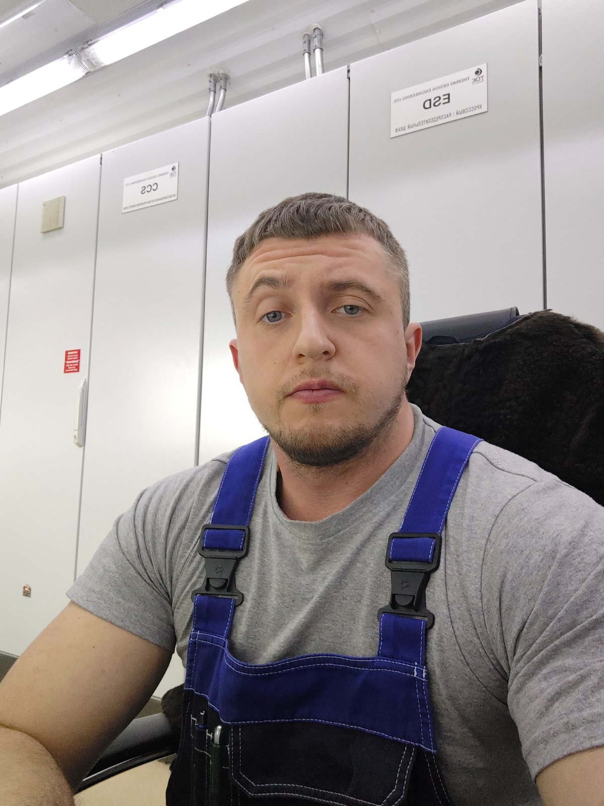 Man in gray shirt observed flexing in office setting