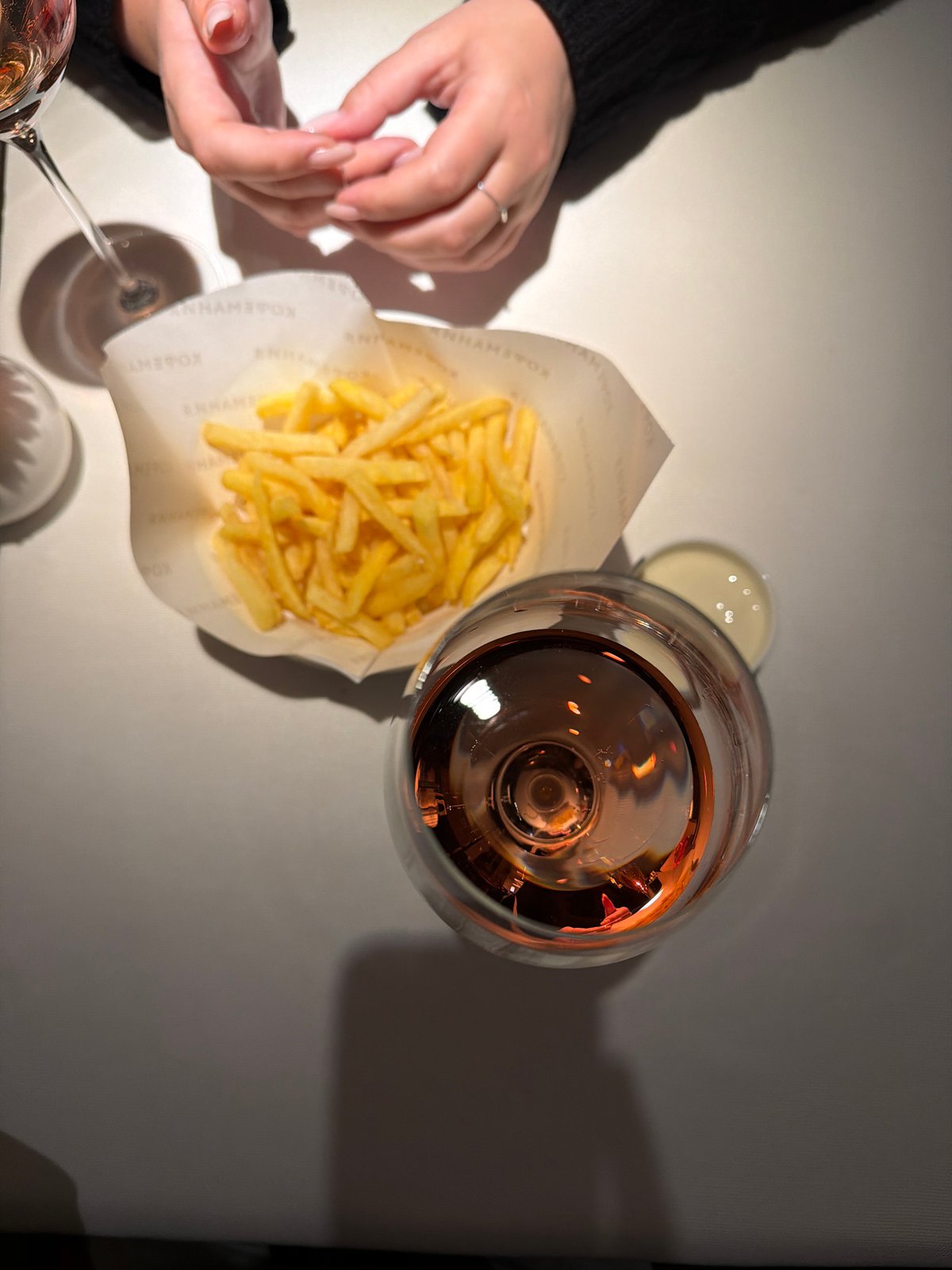 Diner enjoys fries and rosé wine at restaurant