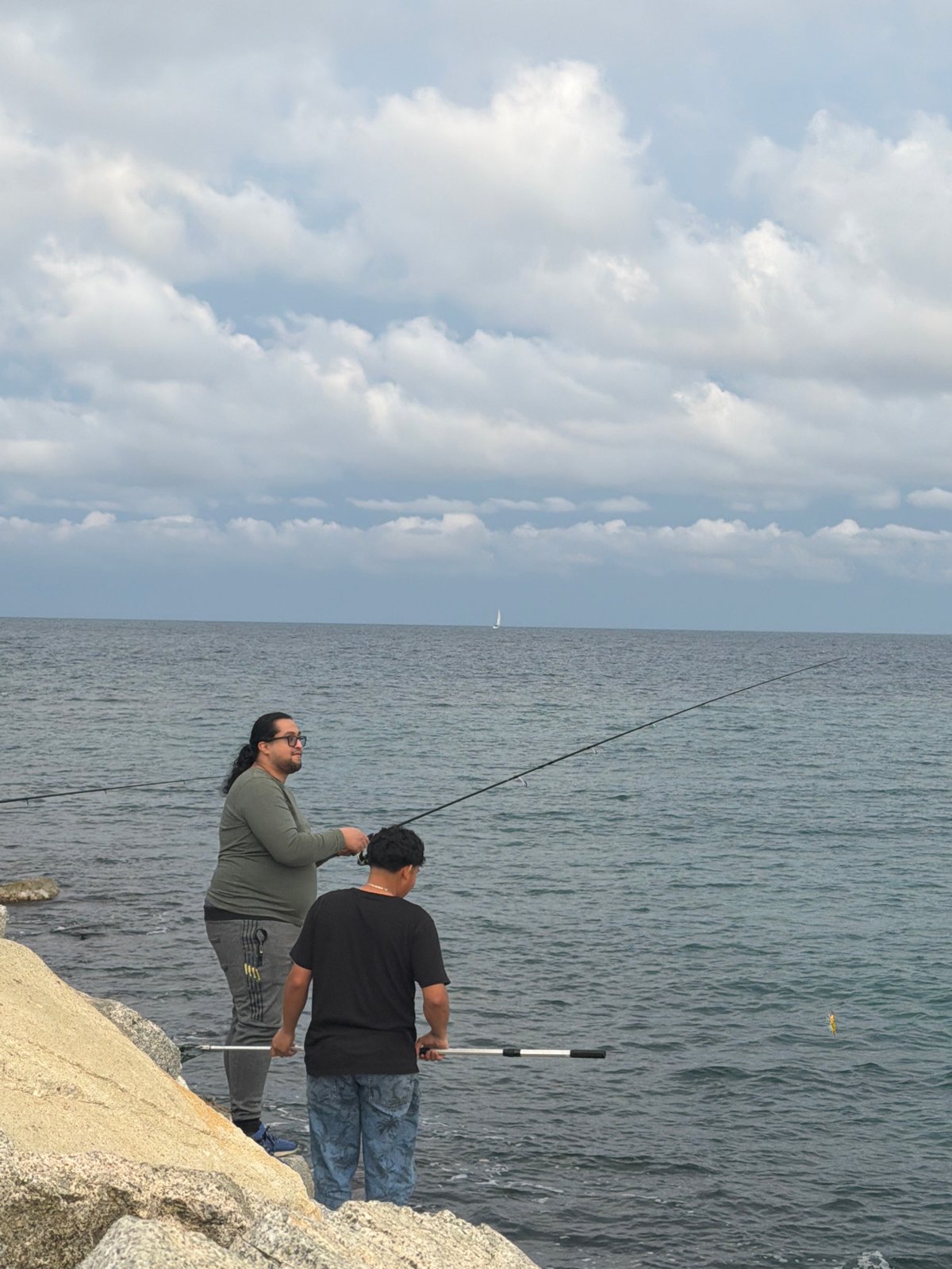 Two anglers fish from Barcelona rocky coast evening