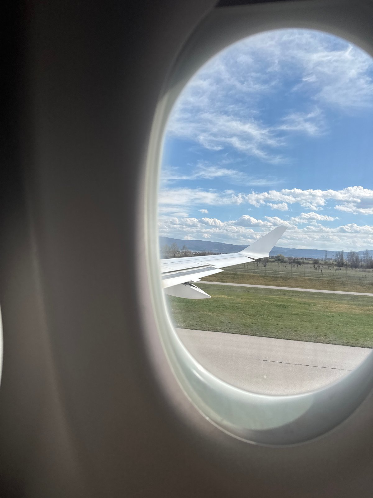 Airplane window view captures Sofia landscape with mountains, runway