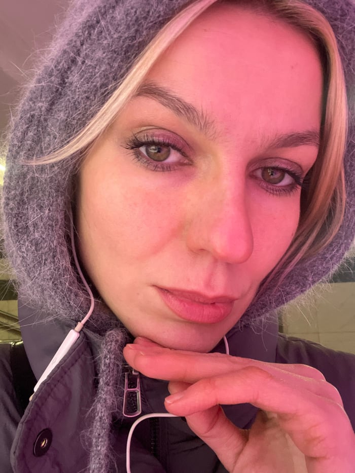 Woman in winter attire photographed under pink lighting in Moscow