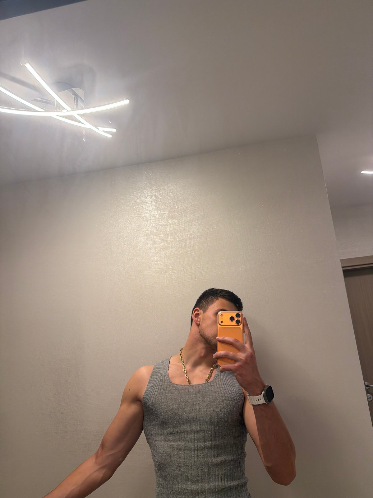 Man takes mirror selfies indoors with orange smartphone