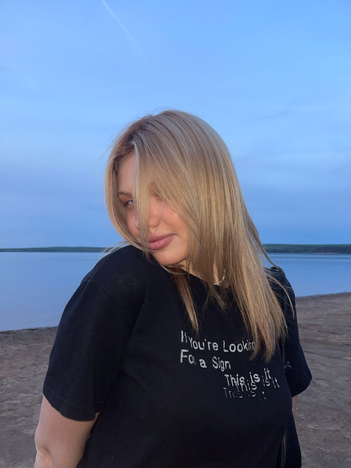 Woman poses for photos at Chaikovsky lakefront during evening