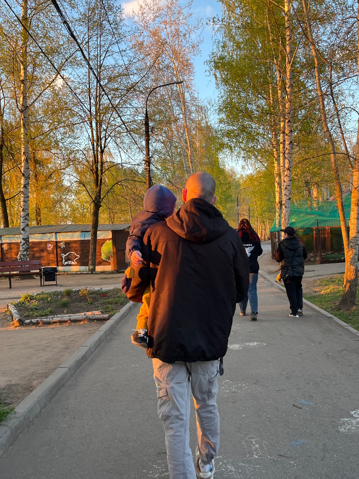Father carries child on back during park walk in Chaikovsky