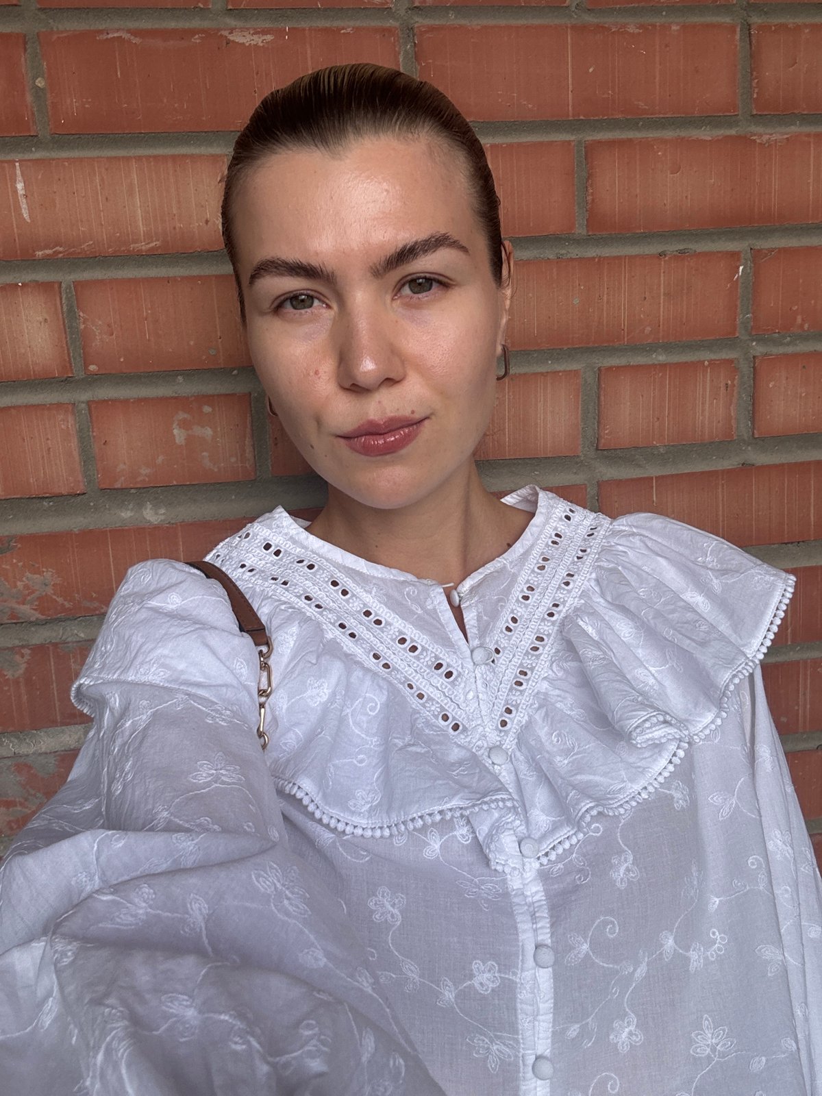 White embroidered blouse against a brick wall backdrop