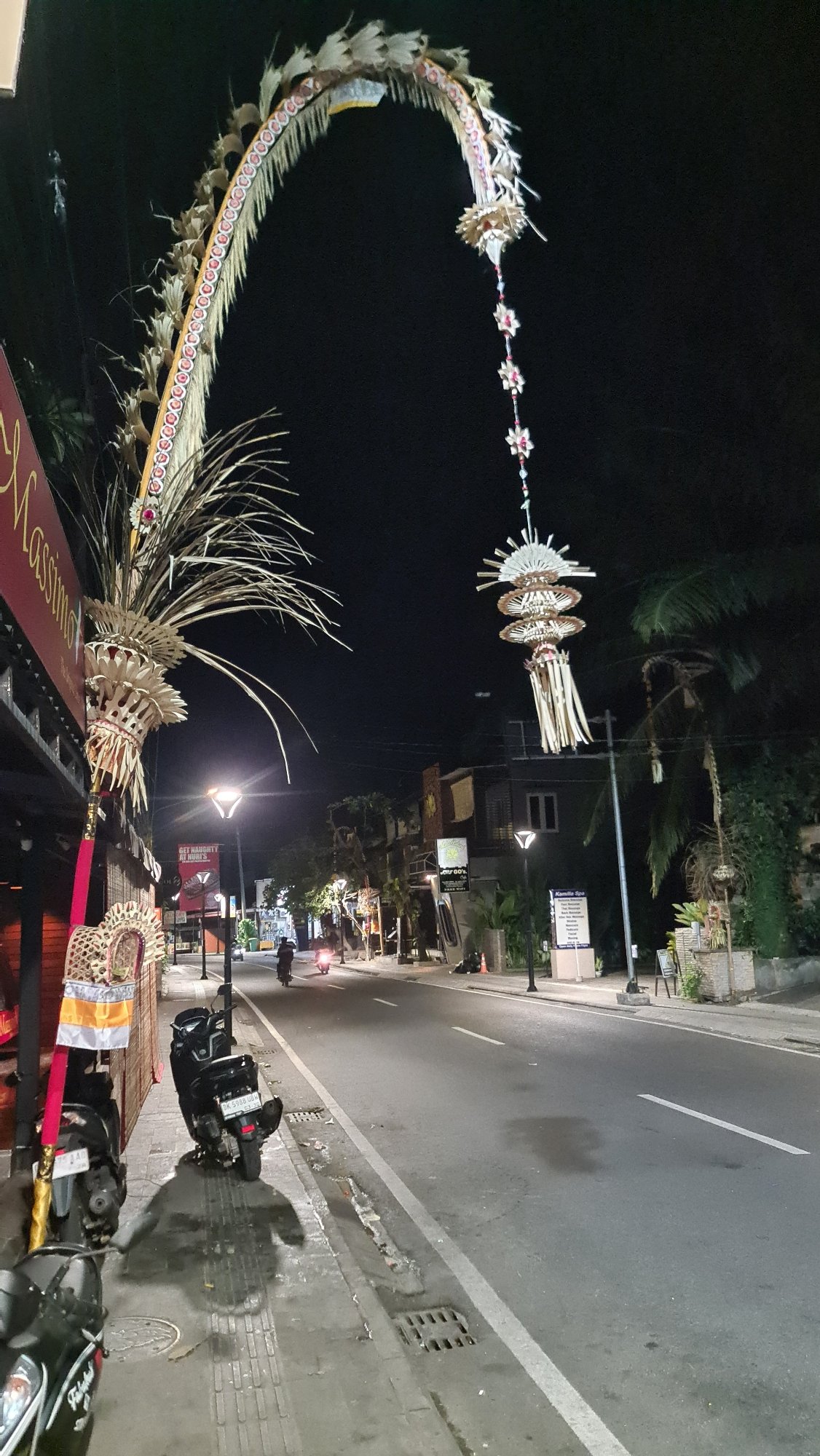 Denpasar streets at night, with Balinese offerings on a parked car