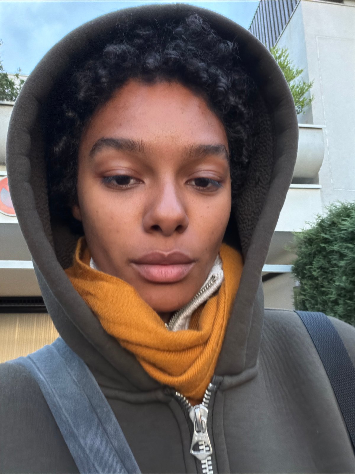 Person in gray hoodie and yellow scarf photographed in France