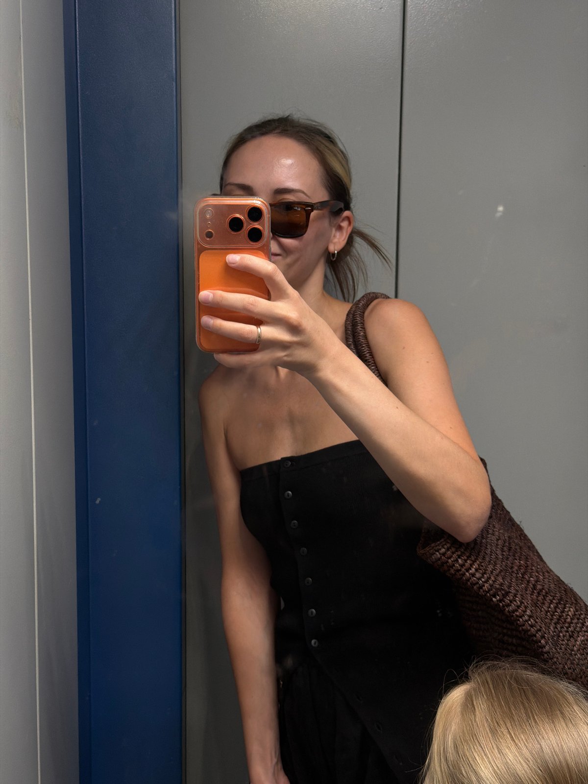 Mirror selfie in Khimki, black top and orange phone in hand