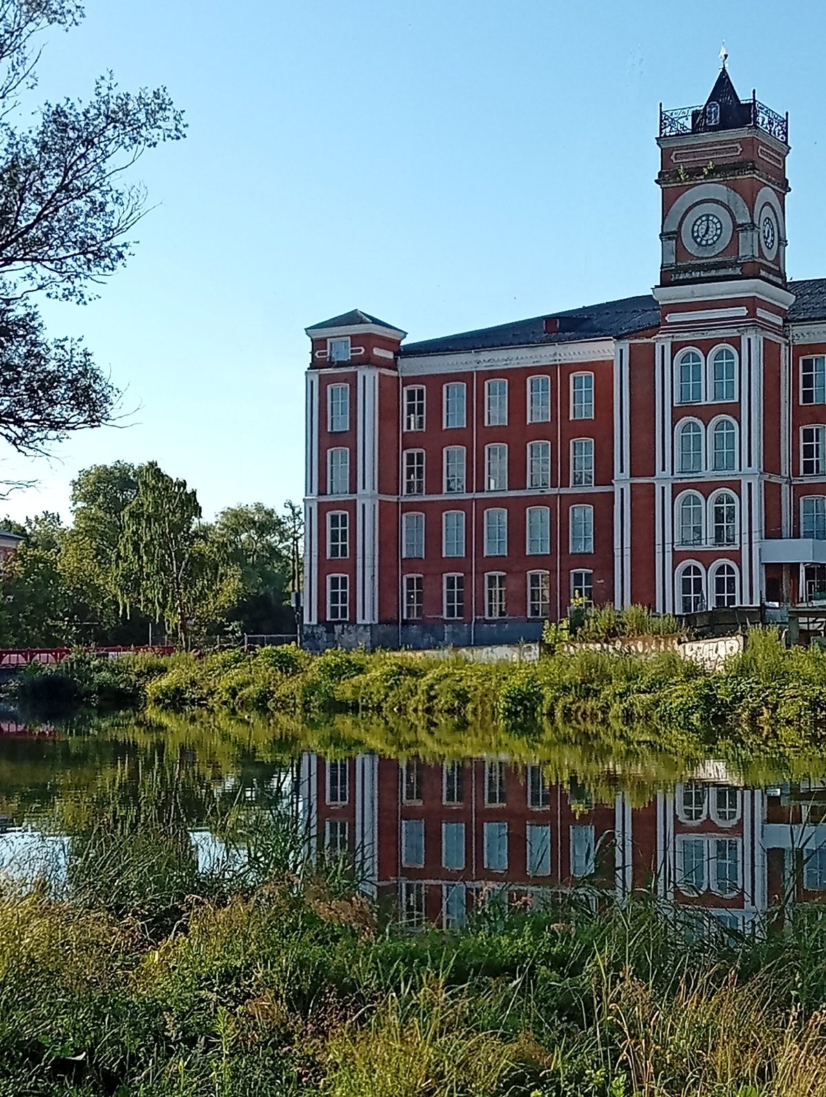 Red brick clock tower building reflected in still water