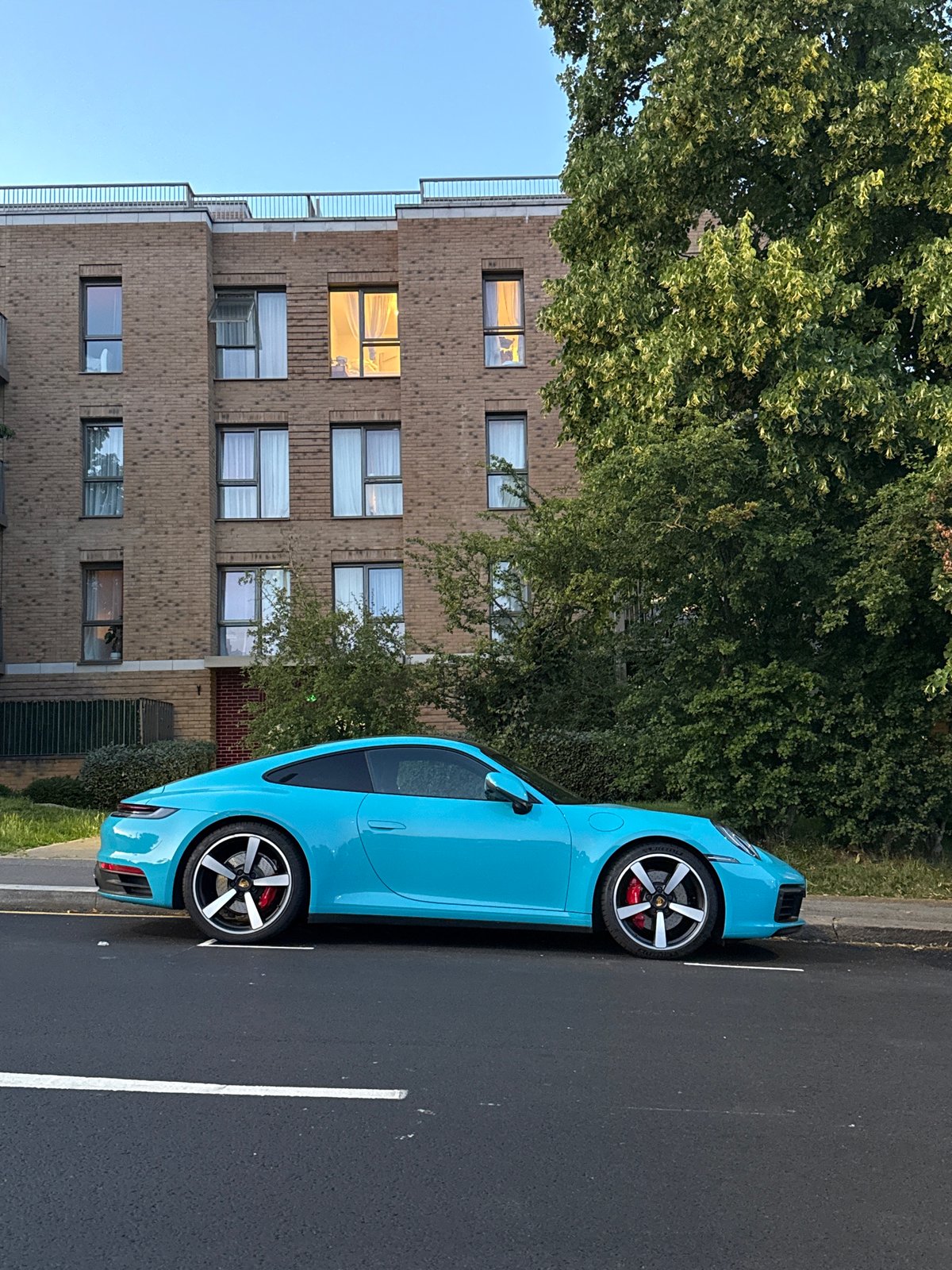 Cyan Porsche and crescent moon on a London summer evening