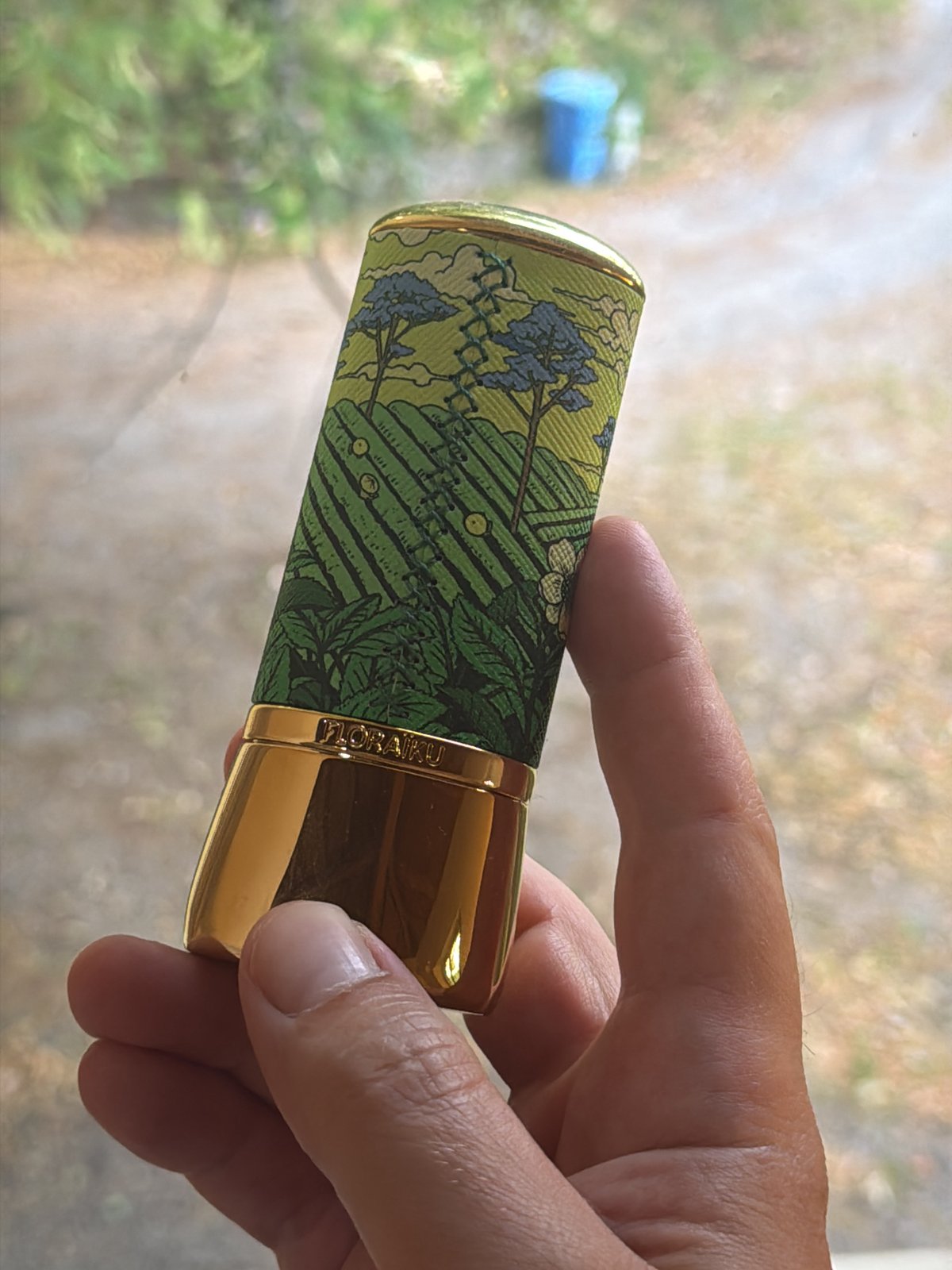 Small golden cylindrical object held up close in Erba