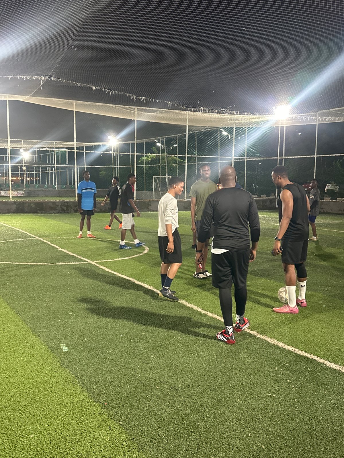 Evening football session on a floodlit astroturf pitch in Abuja