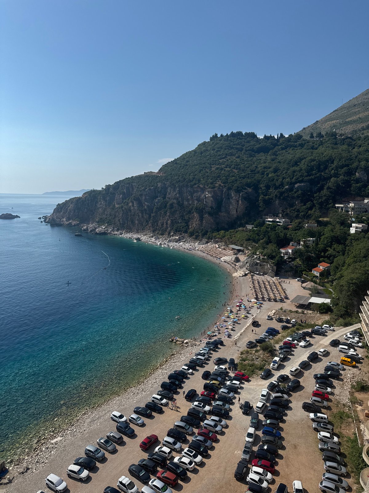 Busy beach day in Mirište, with a graffiti-covered ruin nearby