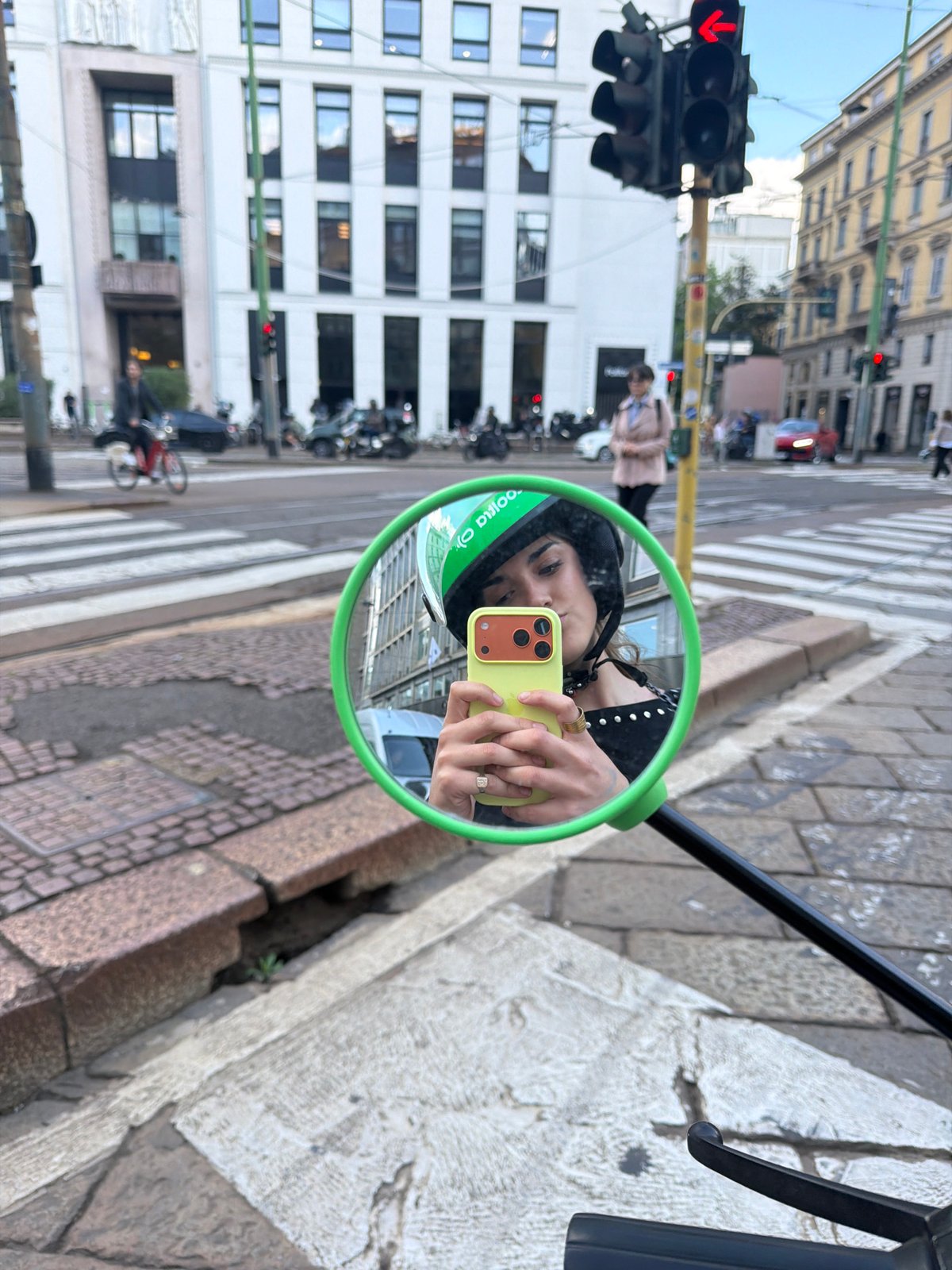 Milan street scene captured in green bike mirror reflection