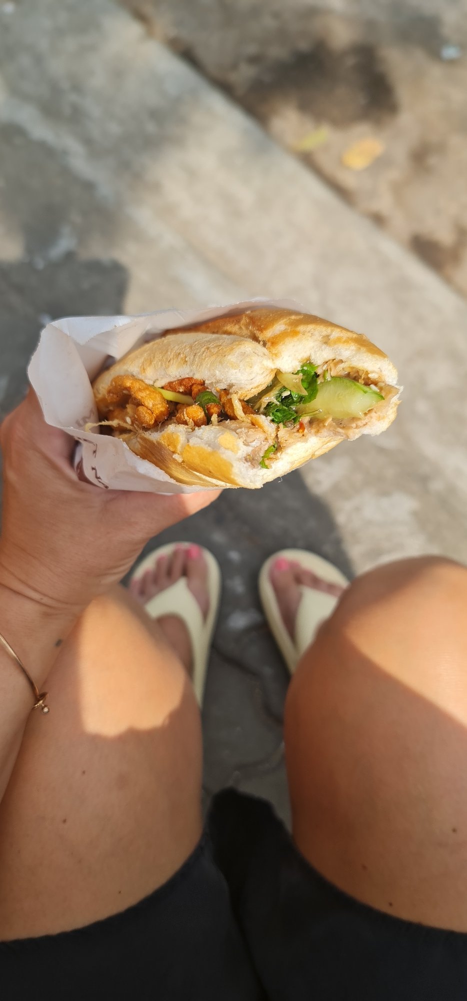 Person enjoys Banh Mi sandwich on Đà Nẵng street